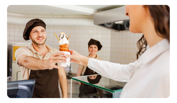 Cajero entregando helado de vainilla a comensal mujer