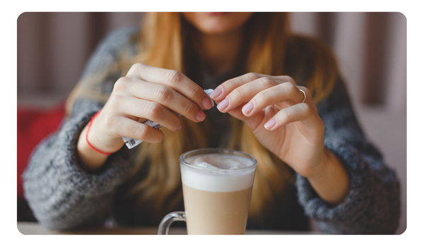 cafe capuchino y mujer agregando azucar